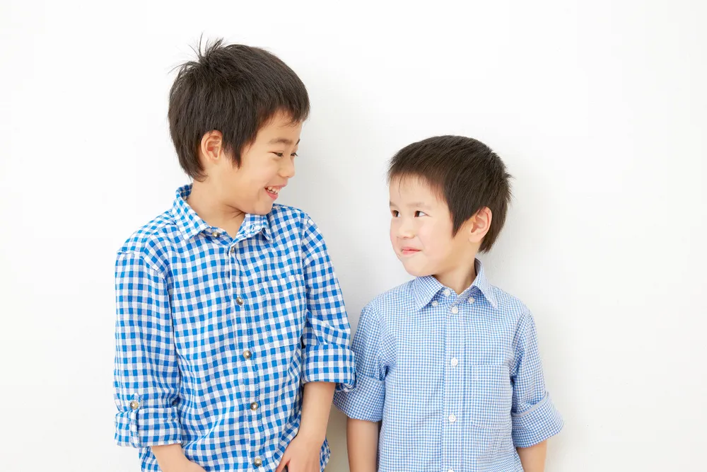 ランドセルを背負った小学生の男の子が、青空の下で道路を元気に走っている様子